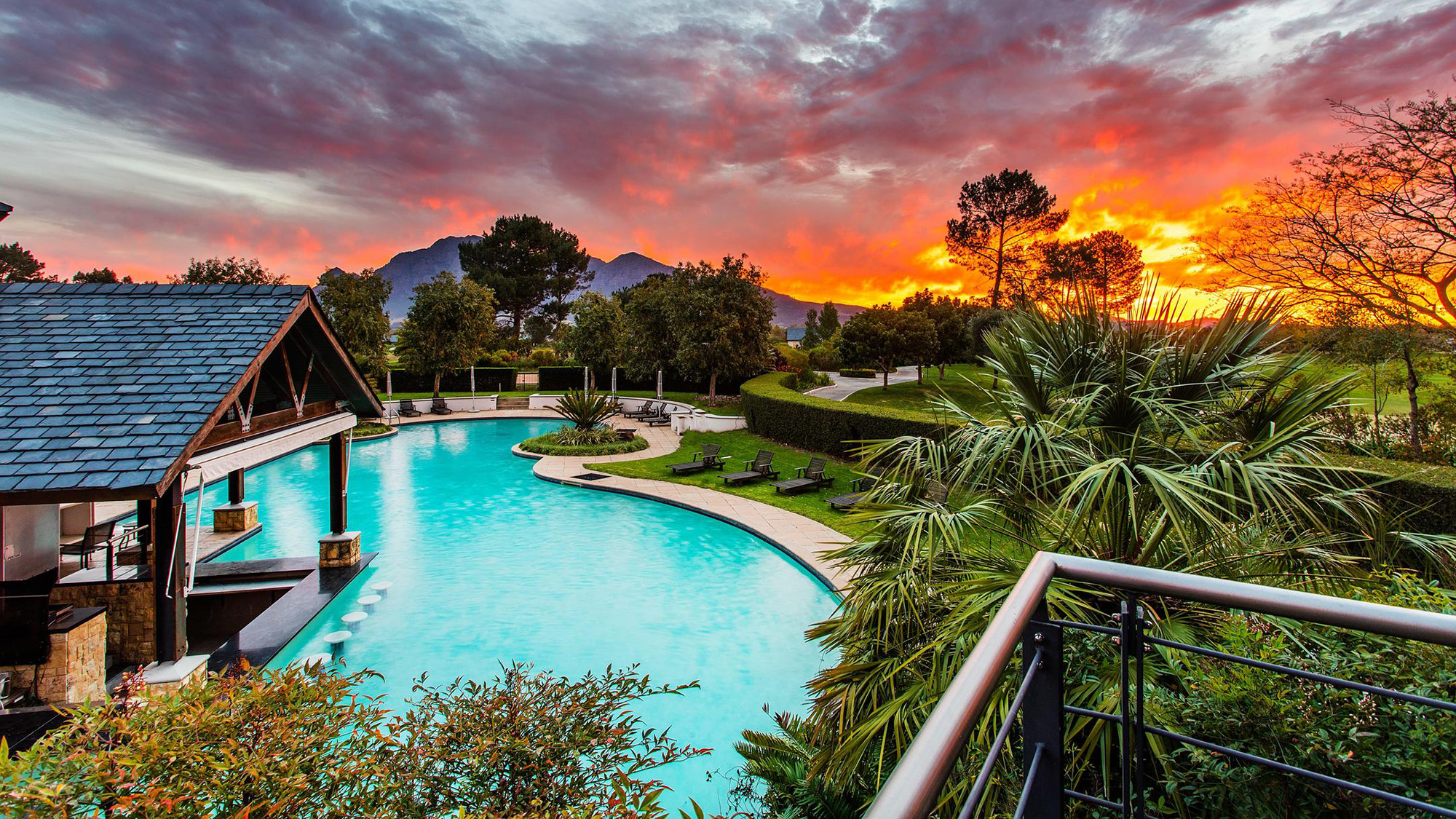 Pool and terrace at a Winelands hotel beneath the Franschhoek mountains at sunset