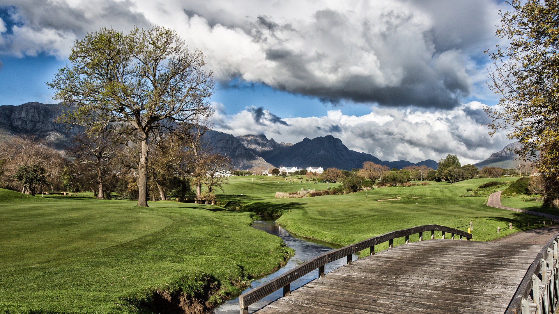 Wooden bridge over a stream on the De Zalze fairways with the Stellenbosch mountains beyond
