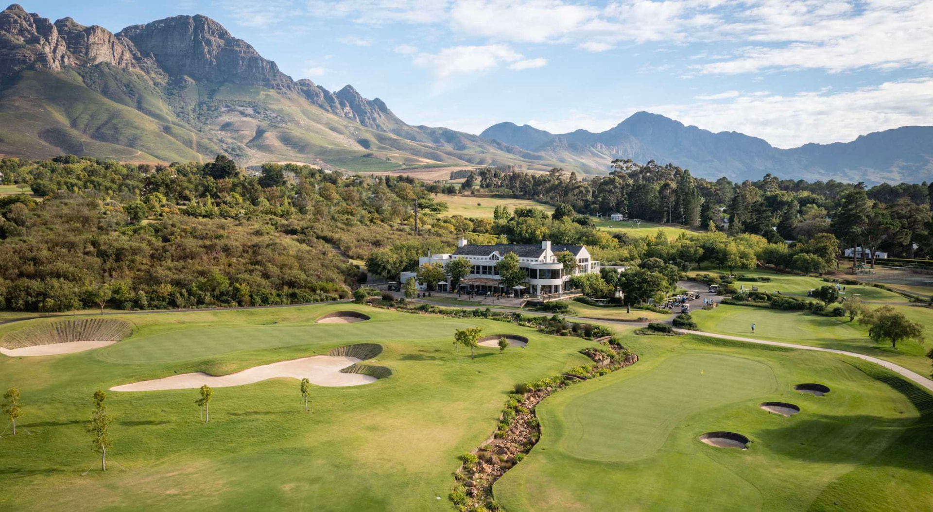 Aerial view of the Erinvale clubhouse, greens and bunkers beneath the Helderberg mountains