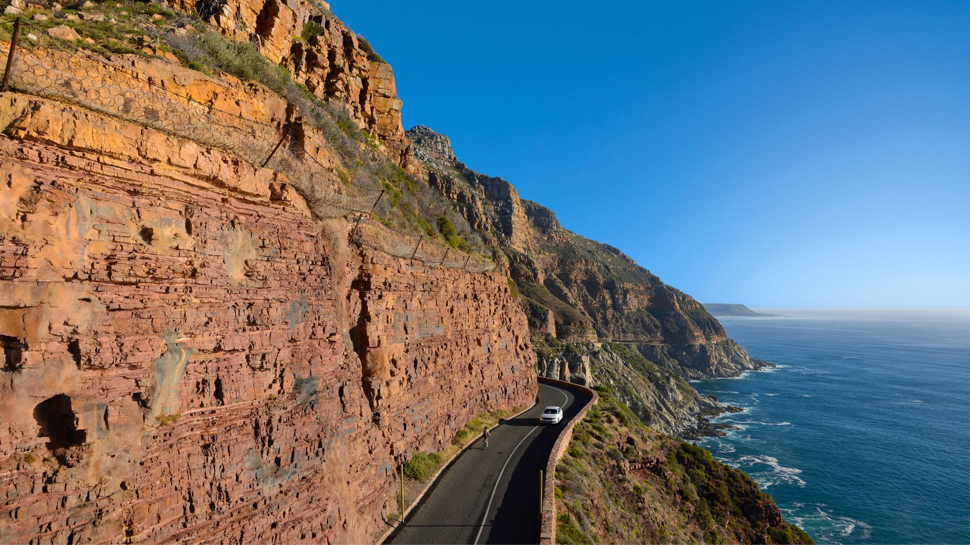 Chapman’s Peak Drive winding beneath dramatic cliffs above the Atlantic at sunset